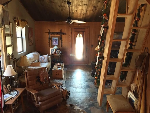 entrance foyer featuring stone tile floors, wooden walls, wood ceiling, and a ceiling fan