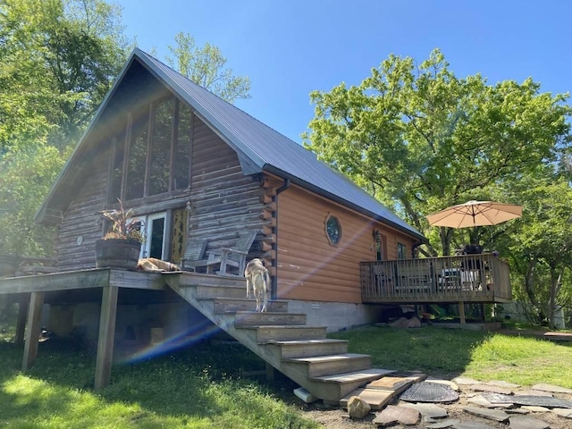 view of property exterior with log siding, a lawn, metal roof, and a wooden deck