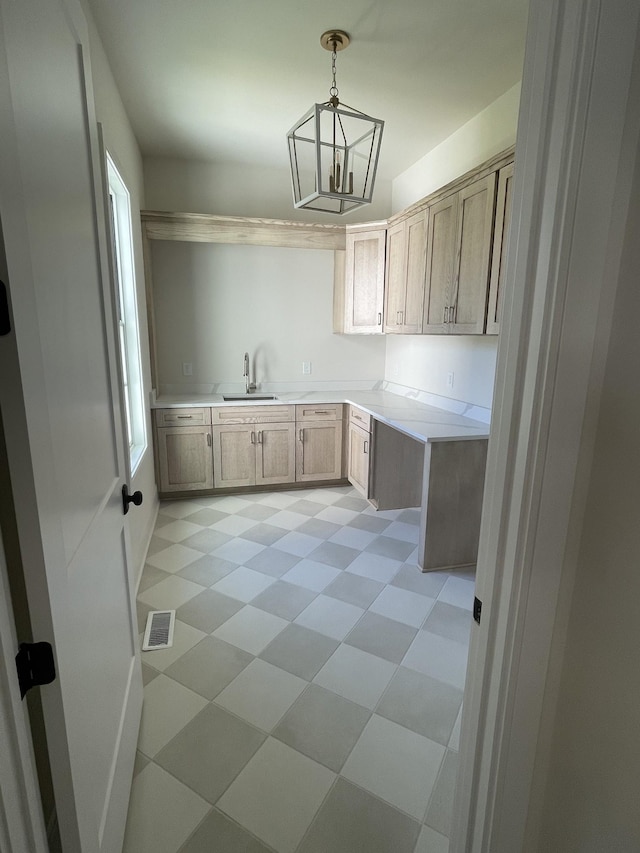 kitchen featuring visible vents, pendant lighting, a sink, light countertops, and light floors