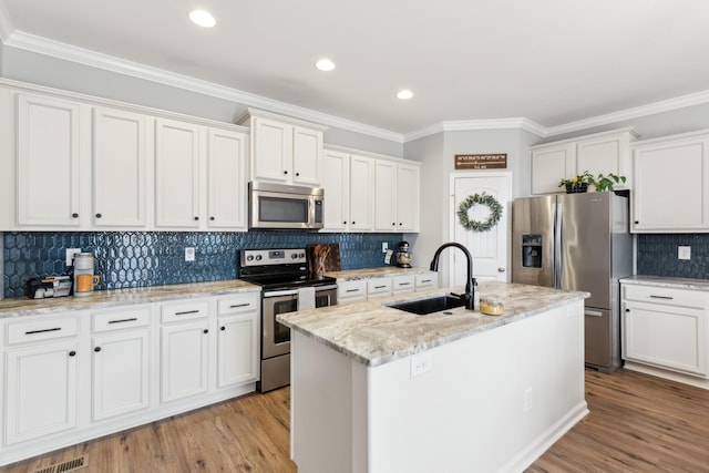 kitchen featuring light wood finished floors, an island with sink, white cabinets, stainless steel appliances, and a sink