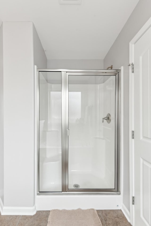 bathroom with tile patterned floors, baseboards, and a stall shower