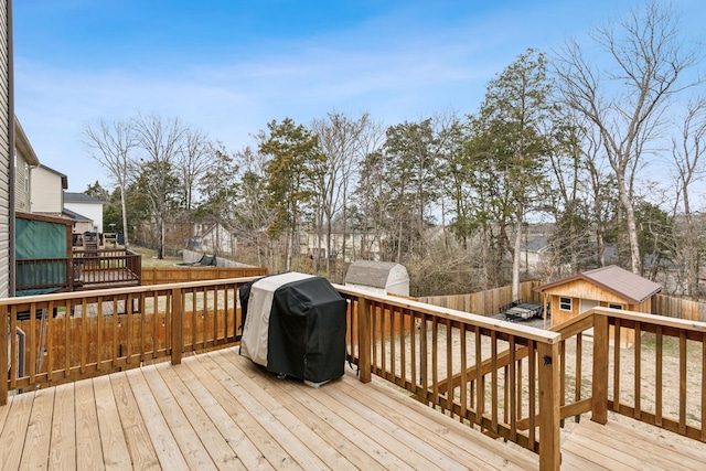 wooden terrace with a storage shed, an outdoor structure, fence, and grilling area