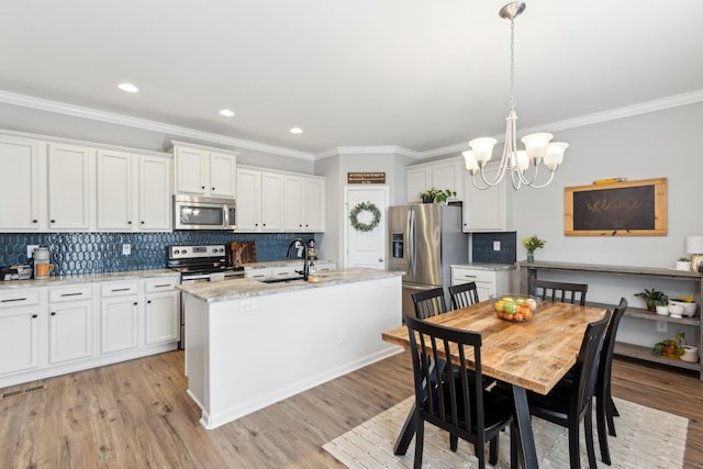 kitchen with light wood finished floors, a center island with sink, appliances with stainless steel finishes, and a sink