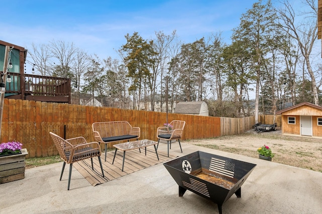 view of patio with an outbuilding, an outdoor living space with a fire pit, and a fenced backyard