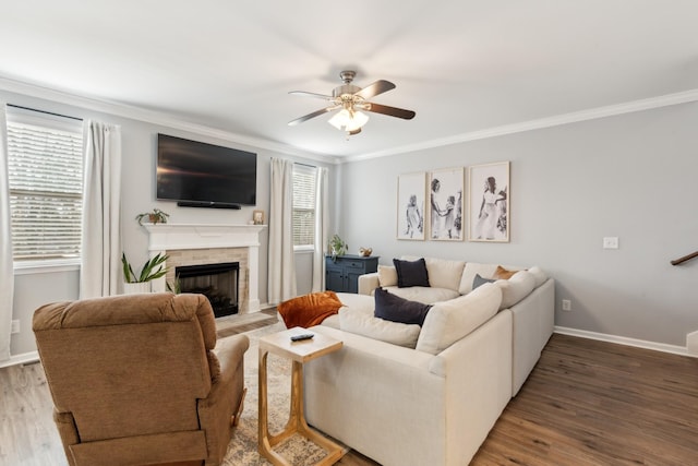 living area featuring a fireplace, crown molding, baseboards, and wood finished floors