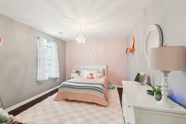 bedroom featuring visible vents, baseboards, wood finished floors, and a chandelier