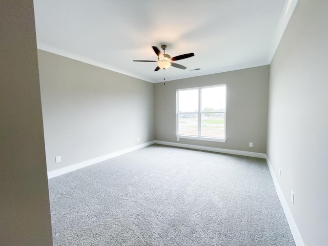 empty room with visible vents, crown molding, baseboards, carpet flooring, and a ceiling fan