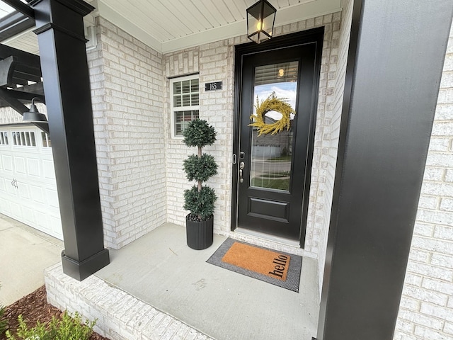 doorway to property featuring brick siding and a porch