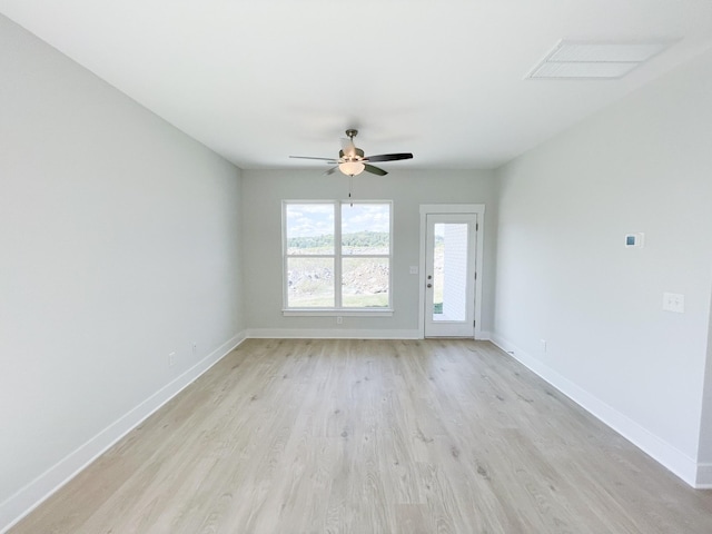 spare room featuring baseboards, ceiling fan, and light wood finished floors