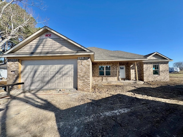 ranch-style home with brick siding, an attached garage, and a shingled roof