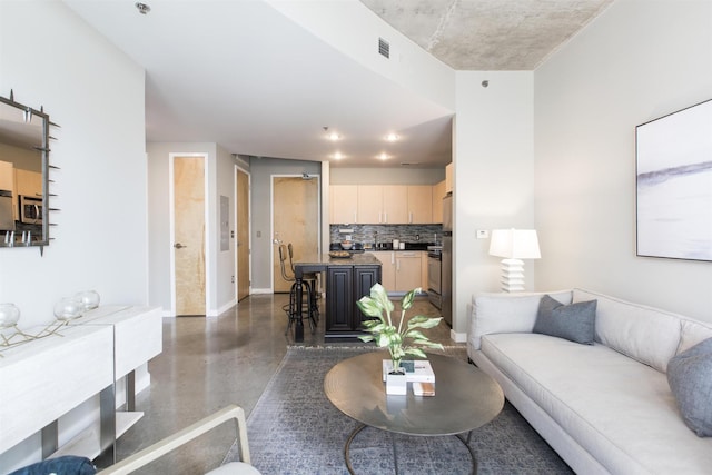 living area featuring visible vents, baseboards, and finished concrete flooring