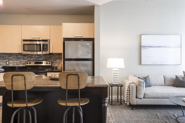 kitchen featuring stainless steel appliances, tasteful backsplash, a breakfast bar, and open floor plan