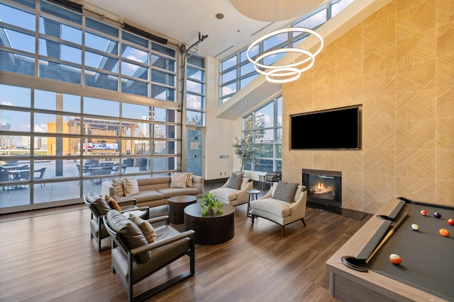 living area with a tiled fireplace, a city view, wood finished floors, and expansive windows