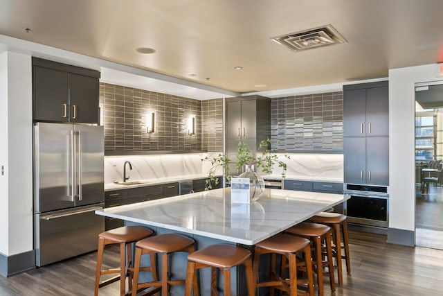 kitchen featuring a breakfast bar area, visible vents, dark wood finished floors, a sink, and appliances with stainless steel finishes