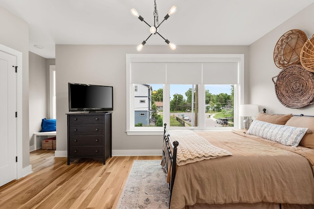 bedroom with light wood-style flooring, a notable chandelier, and baseboards