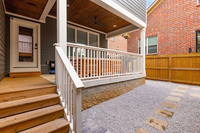 entrance to property featuring brick siding, a porch, and fence