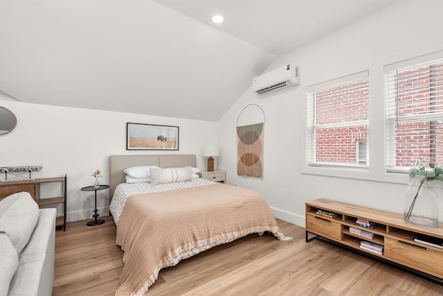 bedroom featuring baseboards, lofted ceiling, light wood-style floors, and an AC wall unit