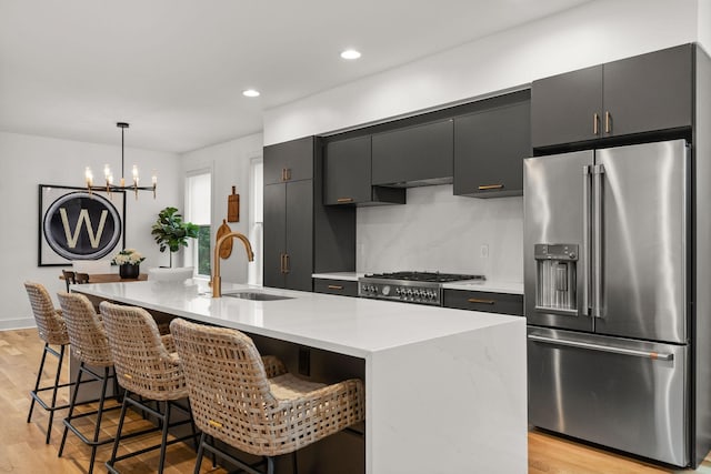 kitchen with light wood finished floors, appliances with stainless steel finishes, light countertops, and a sink