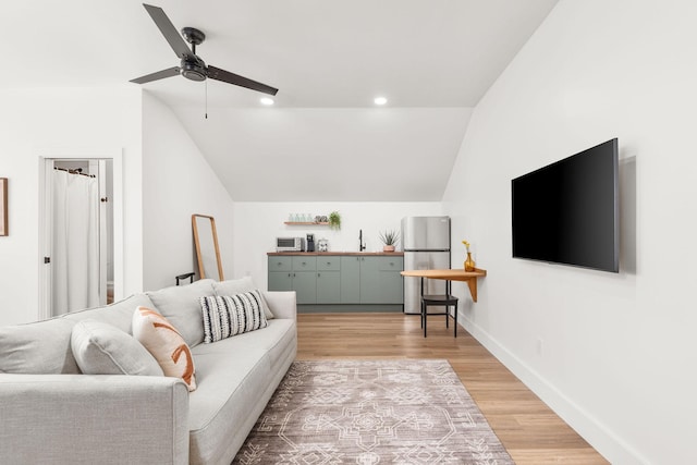 living room featuring recessed lighting, light wood-type flooring, baseboards, and vaulted ceiling