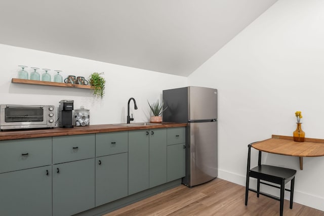 kitchen with a sink, a toaster, freestanding refrigerator, and wood counters