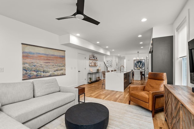 living area featuring recessed lighting, ceiling fan with notable chandelier, and light wood-type flooring