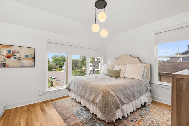 bedroom with baseboards, multiple windows, lofted ceiling, and wood finished floors