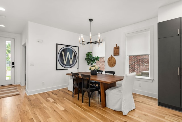 dining room featuring light wood-style flooring, an inviting chandelier, and baseboards