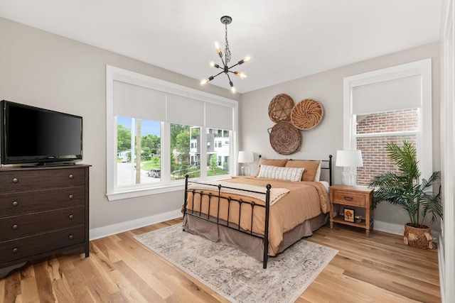 bedroom featuring baseboards, a notable chandelier, and light wood-style flooring