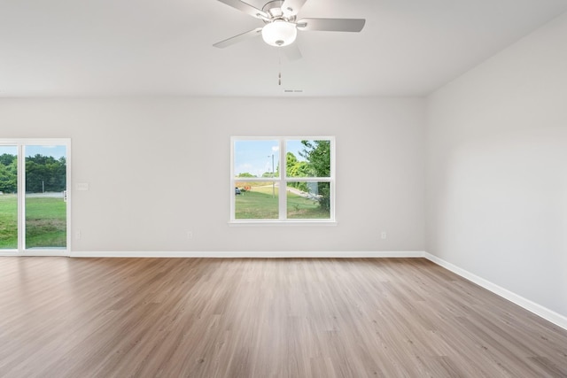 spare room featuring a wealth of natural light, baseboards, wood finished floors, and a ceiling fan