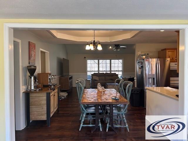 dining room featuring a tray ceiling, a wainscoted wall, dark wood finished floors, and a chandelier