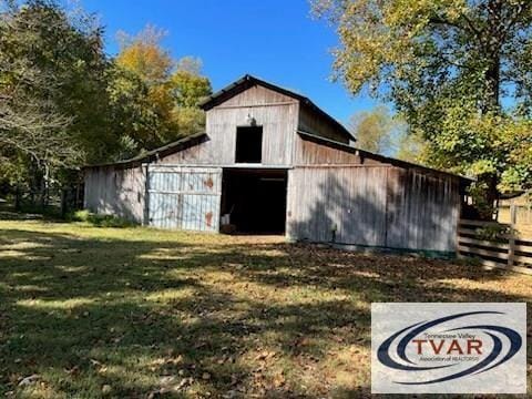 view of barn featuring a lawn and fence