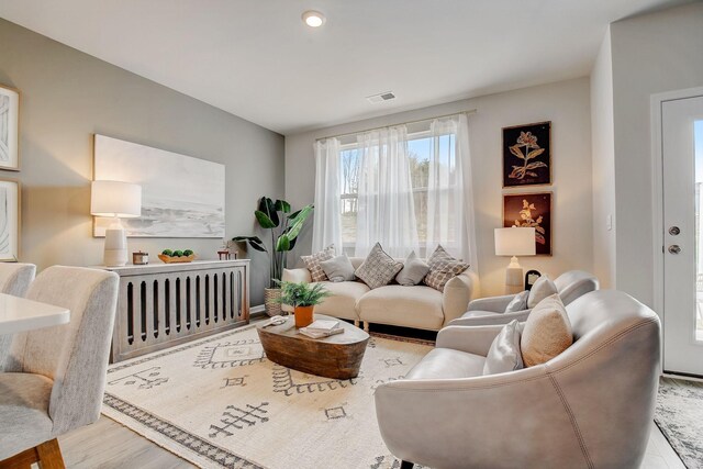 living area featuring visible vents, wood finished floors, and radiator heating unit