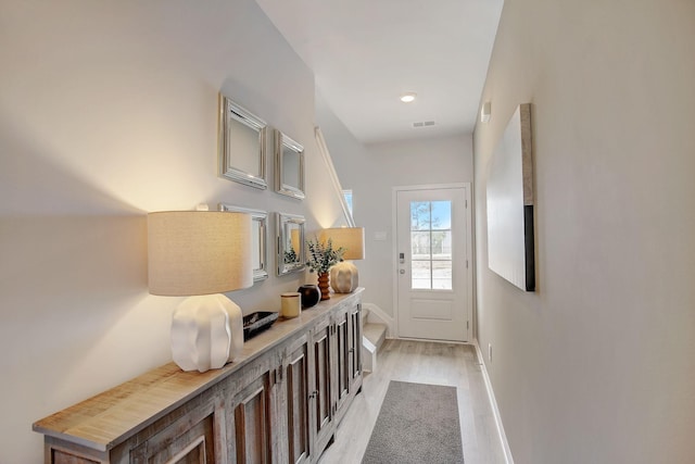 doorway to outside featuring light wood-type flooring, visible vents, and baseboards