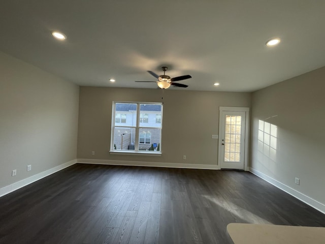 spare room with dark wood-style floors, a healthy amount of sunlight, and baseboards