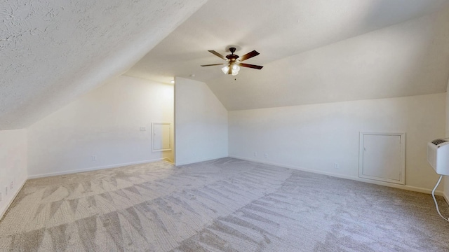 additional living space featuring lofted ceiling, carpet flooring, baseboards, and a textured ceiling