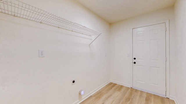 laundry room with electric dryer hookup, baseboards, light wood-style floors, and laundry area