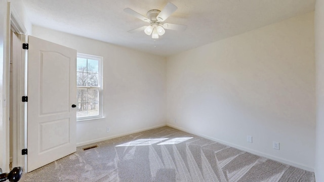 spare room with visible vents, carpet floors, baseboards, and ceiling fan