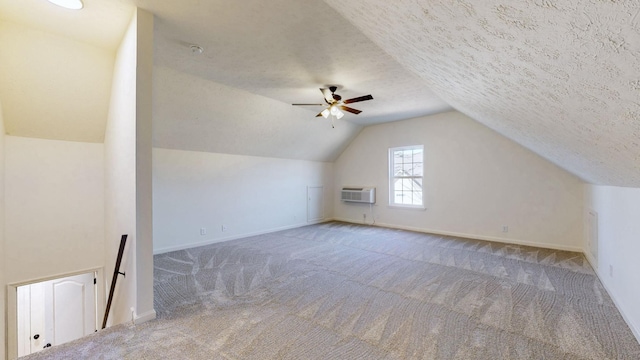 additional living space featuring carpet flooring, a textured ceiling, a wall mounted AC, and vaulted ceiling