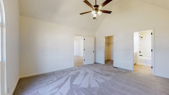 unfurnished bedroom with high vaulted ceiling, ensuite bath, a spacious closet, a closet, and carpet flooring