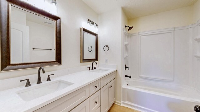 bathroom with bathtub / shower combination, double vanity, and a sink