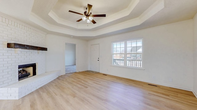 unfurnished living room featuring a raised ceiling, crown molding, a fireplace, and visible vents