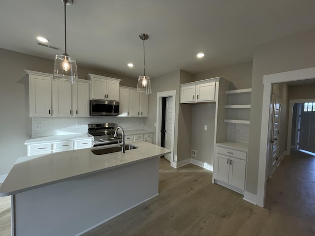 kitchen featuring visible vents, a sink, wood finished floors, white cabinetry, and stainless steel appliances