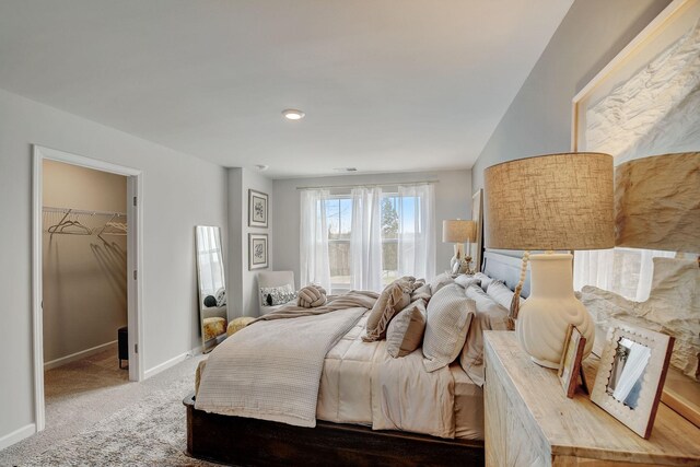 carpeted bedroom with baseboards and a spacious closet