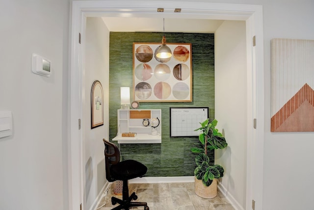 bathroom with baseboards, an accent wall, and wallpapered walls