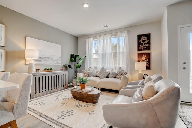 living area with visible vents, wood finished floors, and radiator heating unit