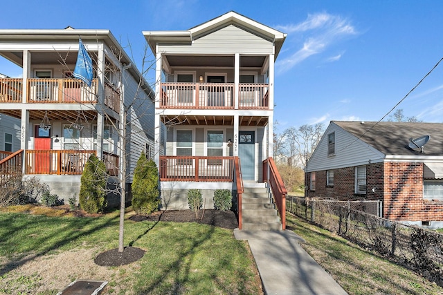 view of front of home with a balcony, a porch, a front yard, and fence