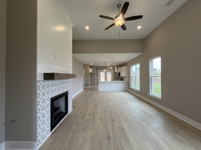 unfurnished living room featuring light wood-type flooring, baseboards, a large fireplace, and visible vents