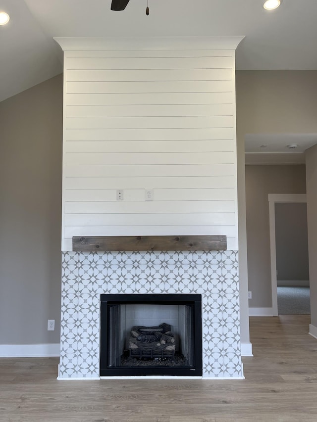 room details with a tiled fireplace, baseboards, and wood finished floors