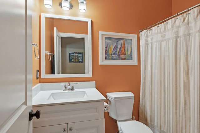 bathroom with curtained shower, toilet, and vanity