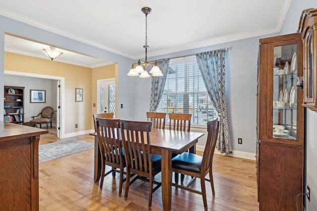 dining area featuring crown molding, light wood-type flooring, and baseboards